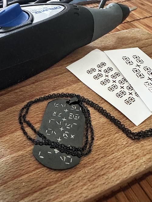 Engraving 12/24 symbols on a small dog tag.